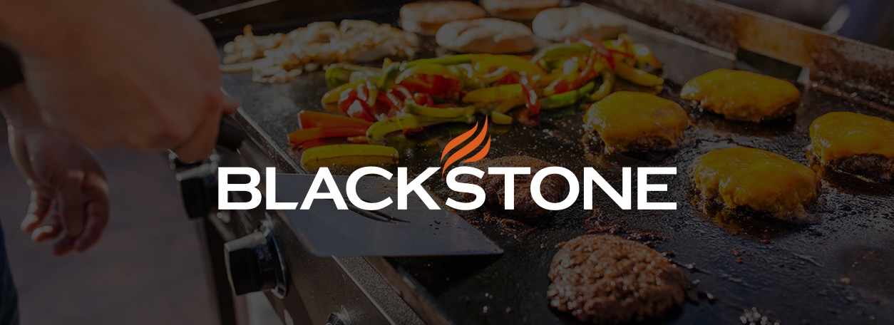 Burgers and griddle peppers sizzle on a Blackstone griddle.